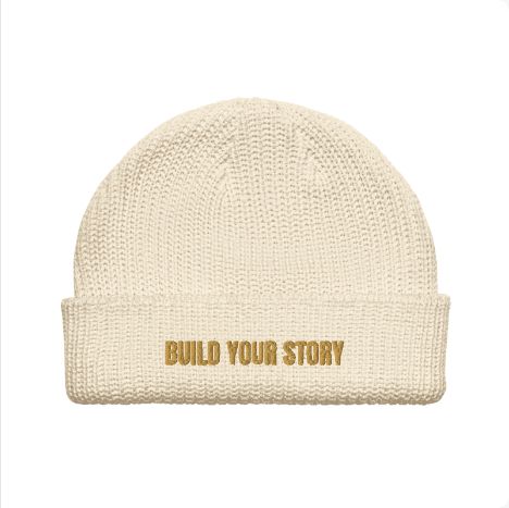 Approved Printful preview: Ecru AS Colour 1120 fisherman beanie with BUILD YOUR STORY in Old Gold embroidery. Final stitch check pending.