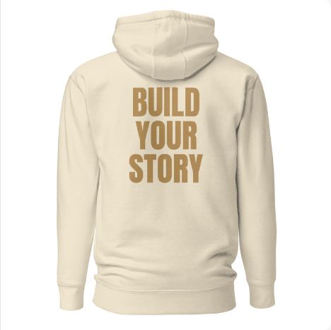 Approved Printful preview: Bone flagship hoodie with warm-gold BUILD YOUR STORY raised on the back.